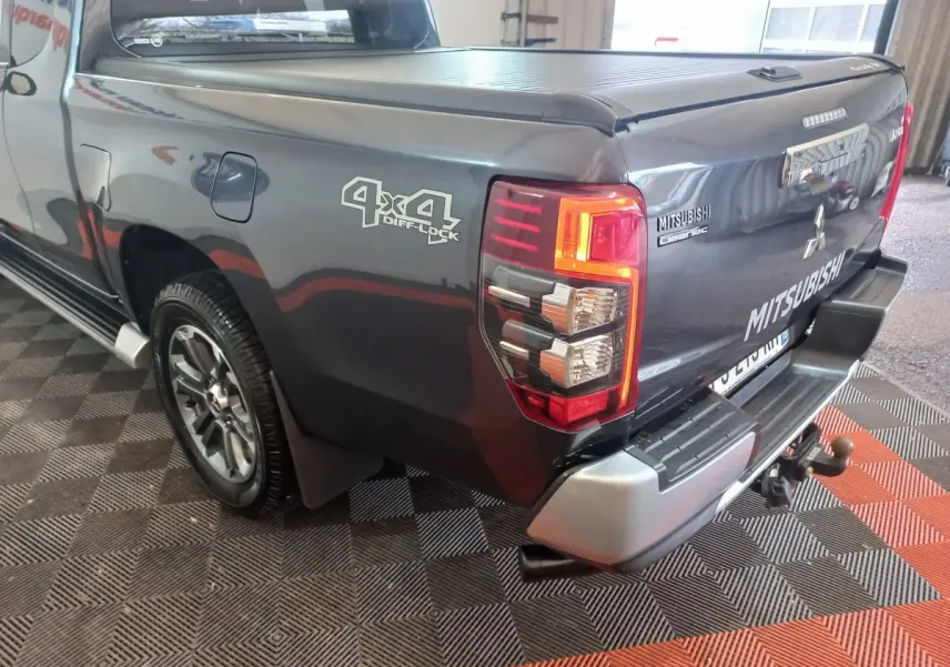Vue 3/4 arrière droite du Mitsubishi L200 gris foncé avec logo 4x4 Diff Lock et benne fermée.