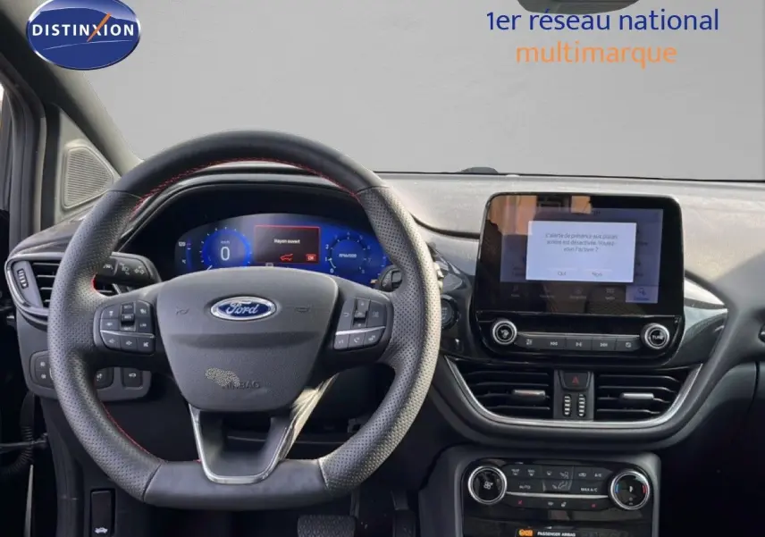 Vue intérieure du tableau de bord et volant noir perforé de la Ford Puma 2023 avec écran tactile central allumé.