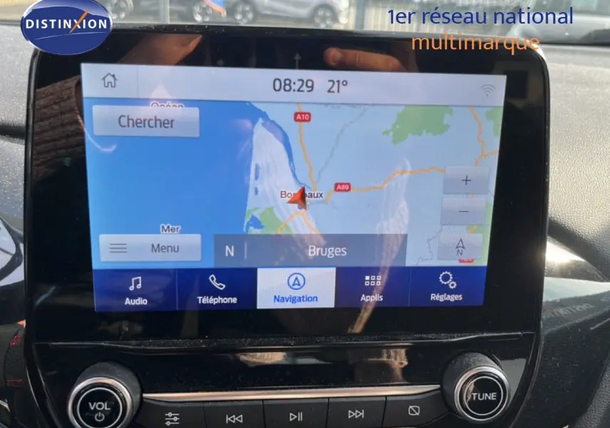 Vue rapprochée de l’écran tactile du Ford Puma noir agate 2023, affichant la navigation GPS vers Bruges.