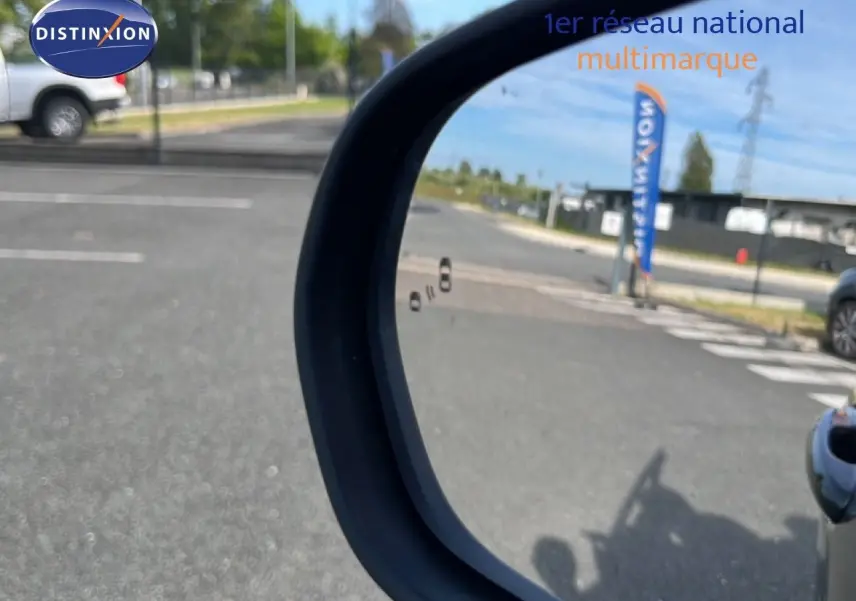 Rétroviseur extérieur droit d’un Ford Puma noir agate métal, avec vue sur un parking et une bannière Distinxion en arrière-plan.