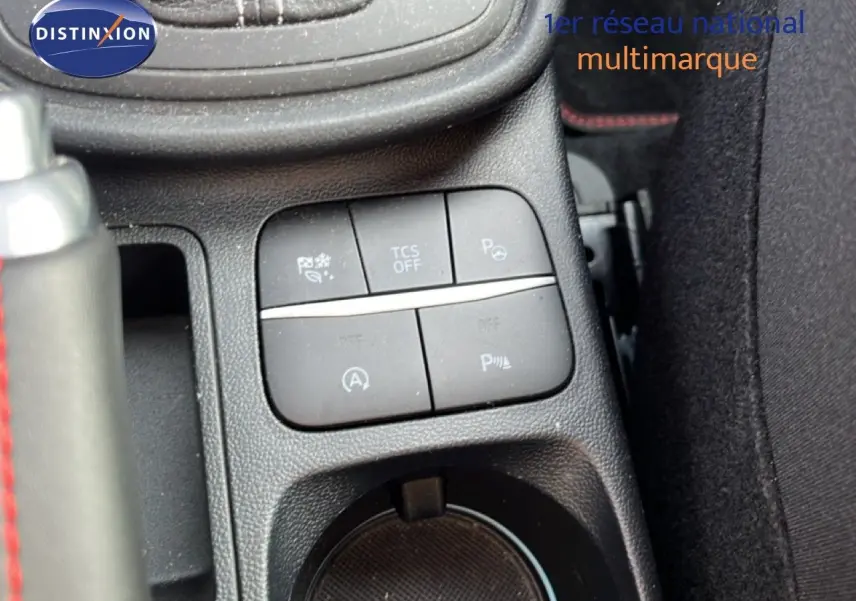 Gros plan sur les commandes centrales et porte-gobelet du Ford Puma noir agate, avec surpiqûres rouges visibles sur le levier.