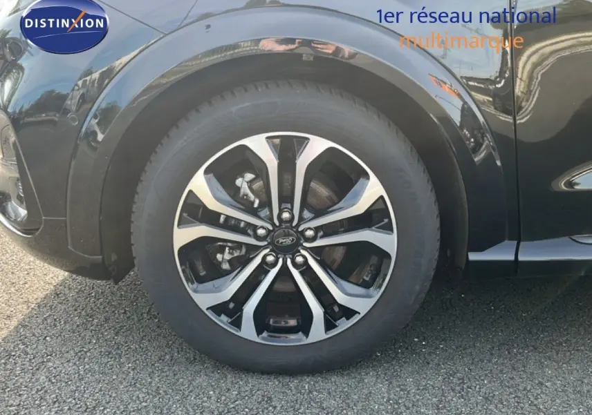 Gros plan sur la roue avant gauche du Ford Puma noir agate métal, mettant en valeur la jante alliage bicolore.
