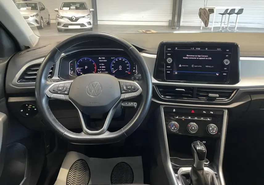 Vue intérieure du tableau de bord et volant cuir noir du Volkswagen T-Roc 2022 avec écran tactile central allumé.
