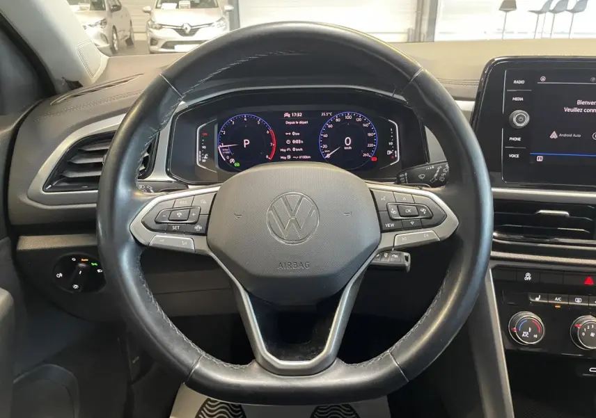 Vue intérieure centrée sur le volant cuir noir multifonction du Volkswagen T-Roc 2022 avec tableau de bord digital.