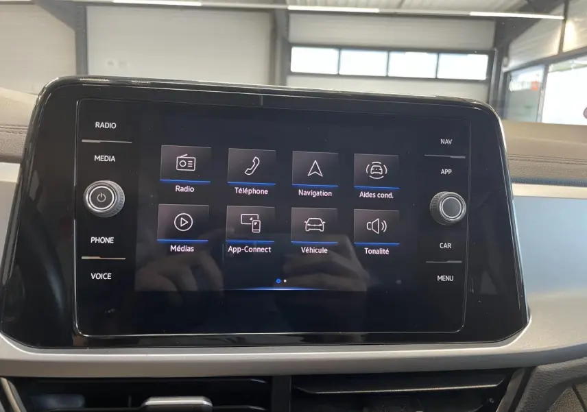 Écran tactile central du Volkswagen T-Roc 2022 affichant les options radio, téléphone, navigation et aides à la conduite.