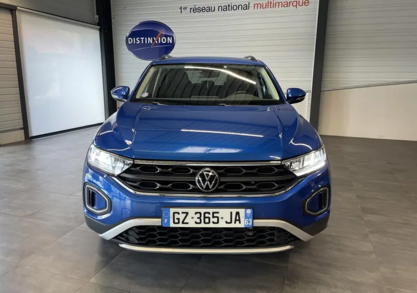 Vue avant d'un Volkswagen T-Roc bleu 2022 avec calandre noire et détails argentés en showroom.