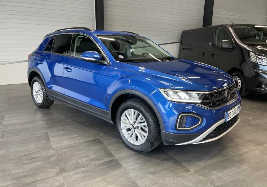 Volkswagen T-Roc bleu en 3/4 avant droit, avec jantes alliage et détails noirs sur les bas de caisse.