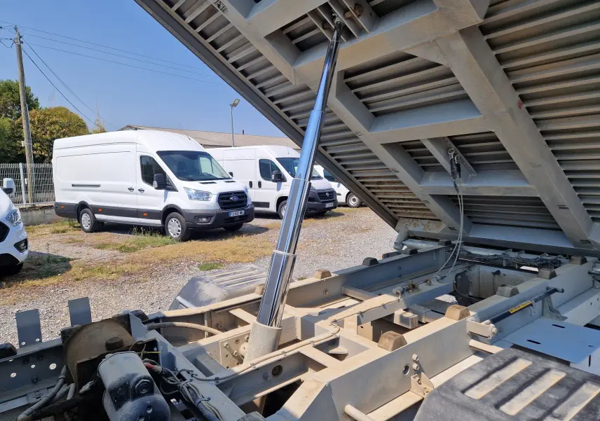 Vue rapprochée du système de basculement de la benne d’un Renault Master blanc, côté arrière droit, en extérieur.