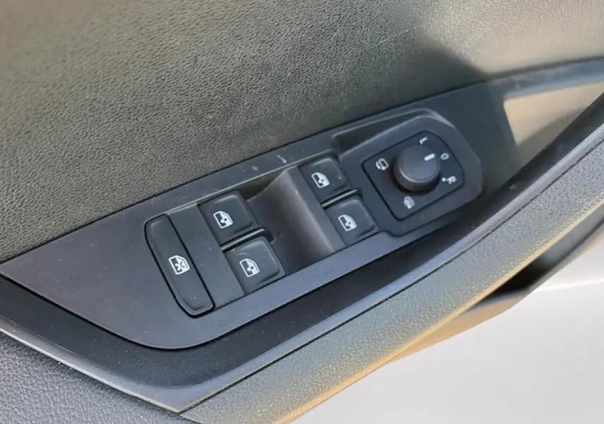 Gros plan sur les commandes des vitres électriques et rétroviseurs côté conducteur du Skoda Karoq gris 2025.