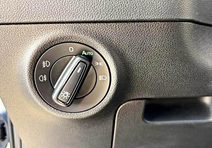 Gros plan sur le bouton de commande des phares dans l’habitacle gris du Skoda Karoq 2025.