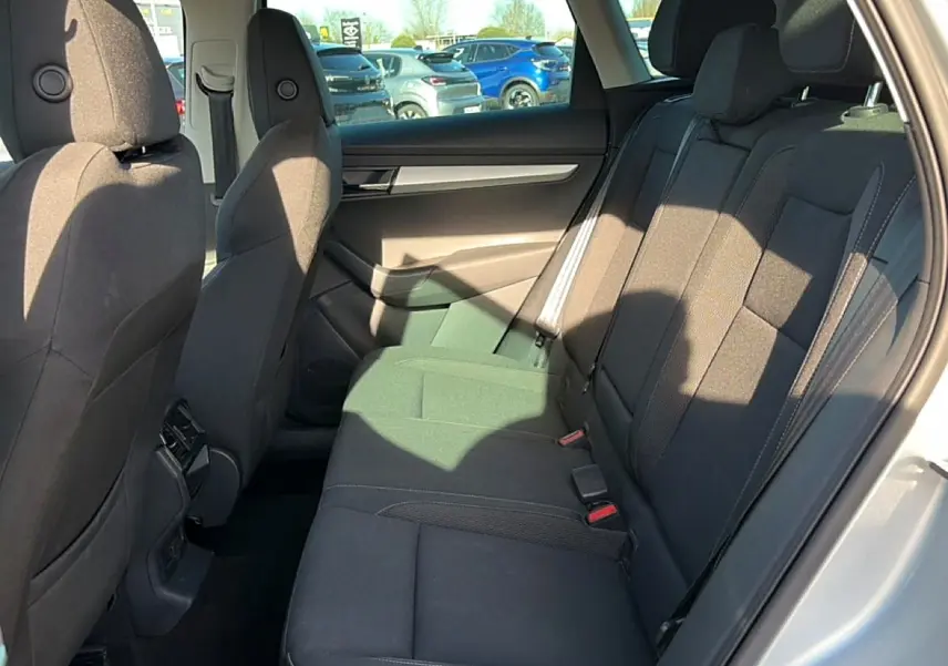 Vue intérieure côté droit des sièges arrière noirs du Skoda Karoq gris 2025 avec appuie-têtes et ceintures visibles.
