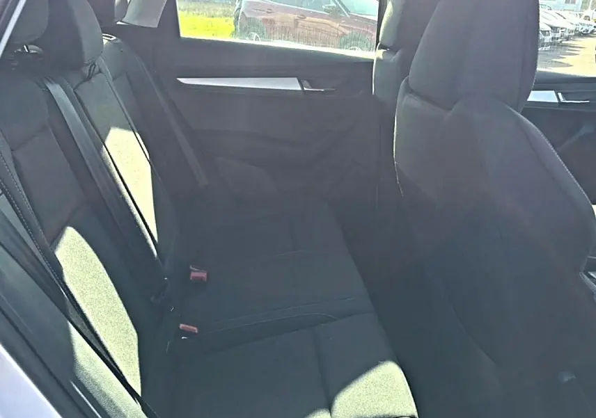 Vue intérieure sur la banquette arrière noire du Skoda Karoq 2025, avec accoudoir central et ceintures visibles.