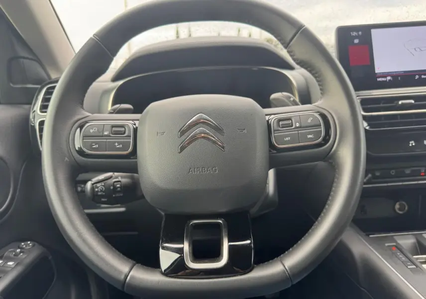 Vue rapprochée du volant multifonction noir du Citroën C5 Aircross 2024 avec commandes intégrées et tableau de bord partiel.