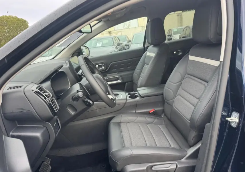Vue intérieure côté conducteur du Citroën C5 Aircross bleu foncé 2024, sièges en cuir et tissu gris avec tableau de bord moderne.