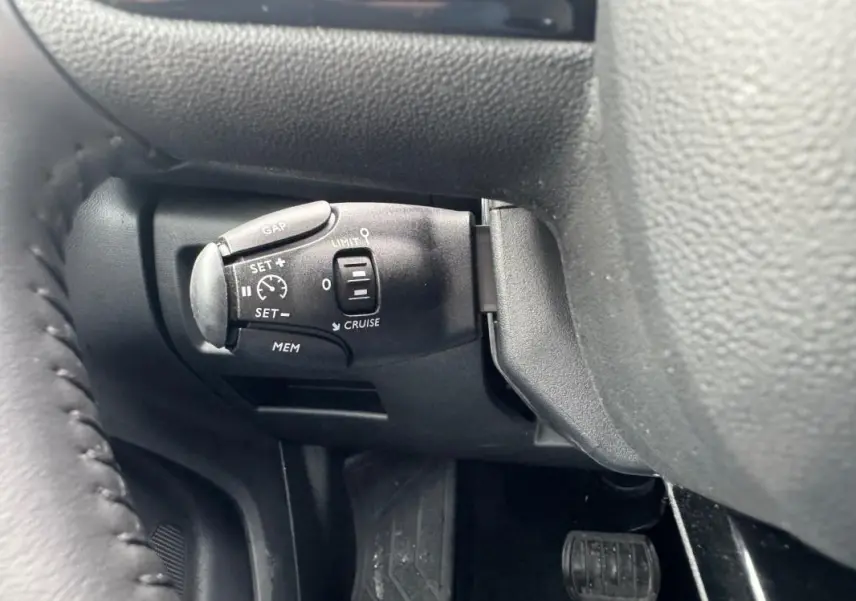Gros plan sur la commande de régulateur de vitesse au volant d’un Citroën C5 Aircross bleu foncé.