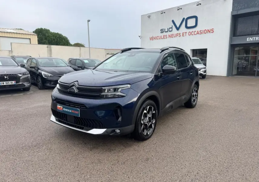 Citroën C5 Aircross hybride bleu foncé en 3/4 avant droit avec barres de toit et jantes alliage 18 pouces.