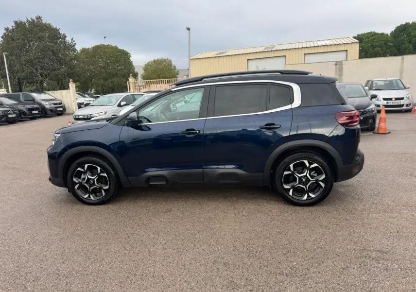 Vue latérale droite d'un Citroën C5 Aircross hybride bleu foncé avec barres de toit et jantes alliage 18 pouces.