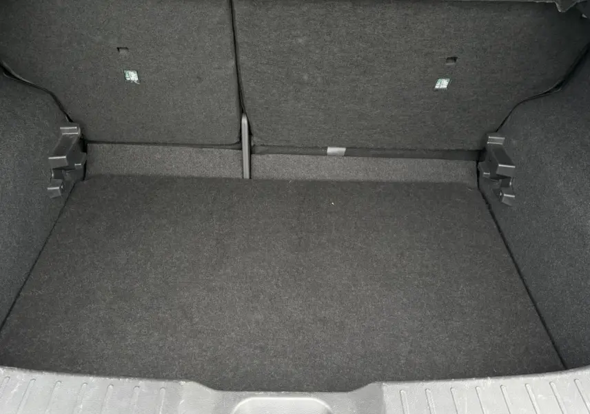 Coffre spacieux et vide du Nissan Juke blanc perle 2023, vue intérieure arrière avec banquette rabattue.