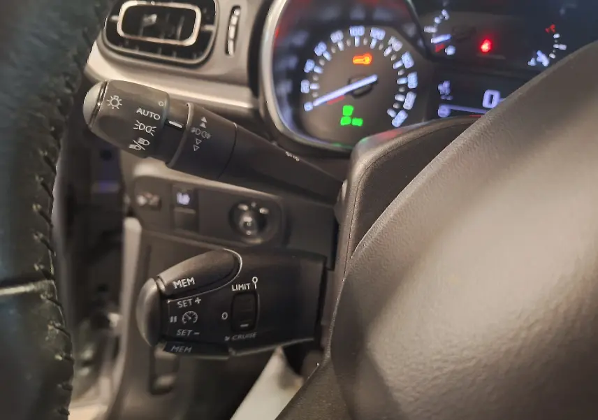 Gros plan sur le volant cuir et les commandes de régulateur de vitesse de la Citroën C3 gris, tableau de bord éclairé.