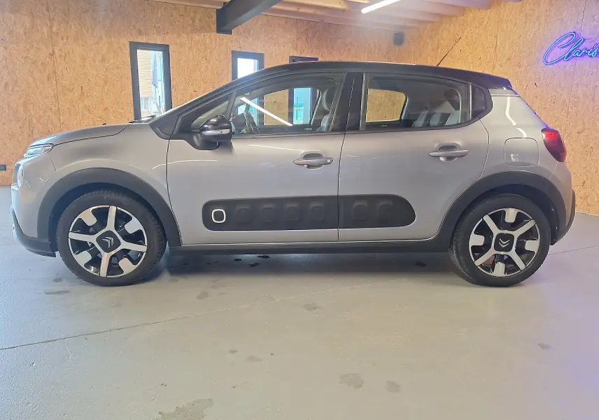 Vue de profil côté gauche d'une Citroën C3 gris avec protections latérales noires et jantes alu stylisées.
