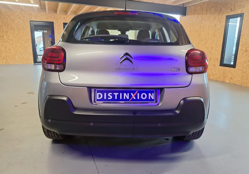 Vue arrière d'une Citroën C3 gris métallisé avec feux arrière distinctifs et pare-chocs noir dans un garage.