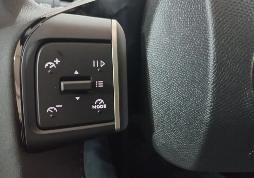 Gros plan sur les commandes de régulateur de vitesse au volant cuir noir d'une Citroën C3 hybride 2025.