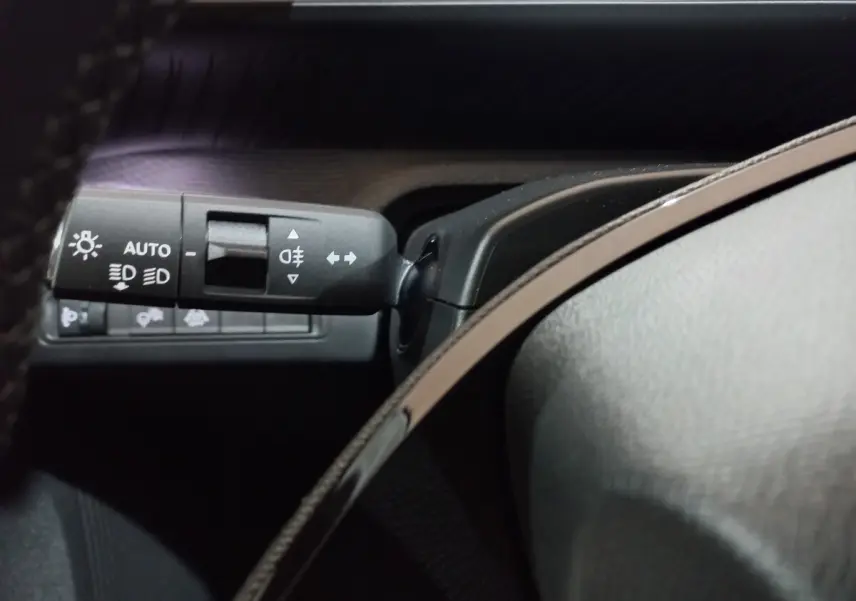 Gros plan sur la commande des feux et clignotants côté gauche du tableau de bord intérieur gris foncé de la Citroën C3 Hybride.