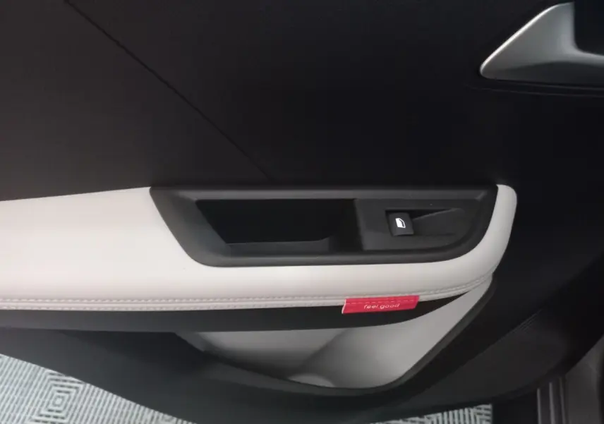 Gros plan sur la poignée intérieure côté gauche de la porte d’une Citroën C3 hybride 2025, garniture noir et gris clair.