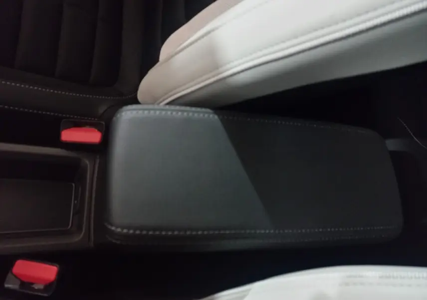 Vue rapprochée de l'accoudoir central noir entre les sièges avant gris clair de la Citroën C3 hybride 2025.