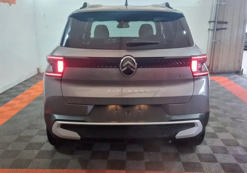 Vue arrière d'une Citroën C3 gris foncé avec feux allumés dans un garage au sol damier noir et orange.