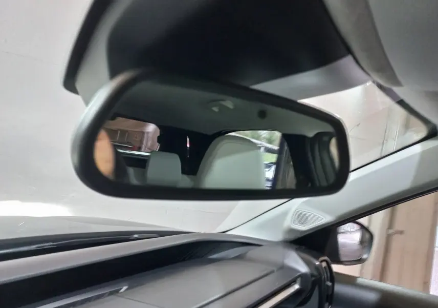 Vue intérieure centrée sur le rétroviseur intérieur d'une Citroën C3 gris foncé, avec siège arrière visible en reflet.