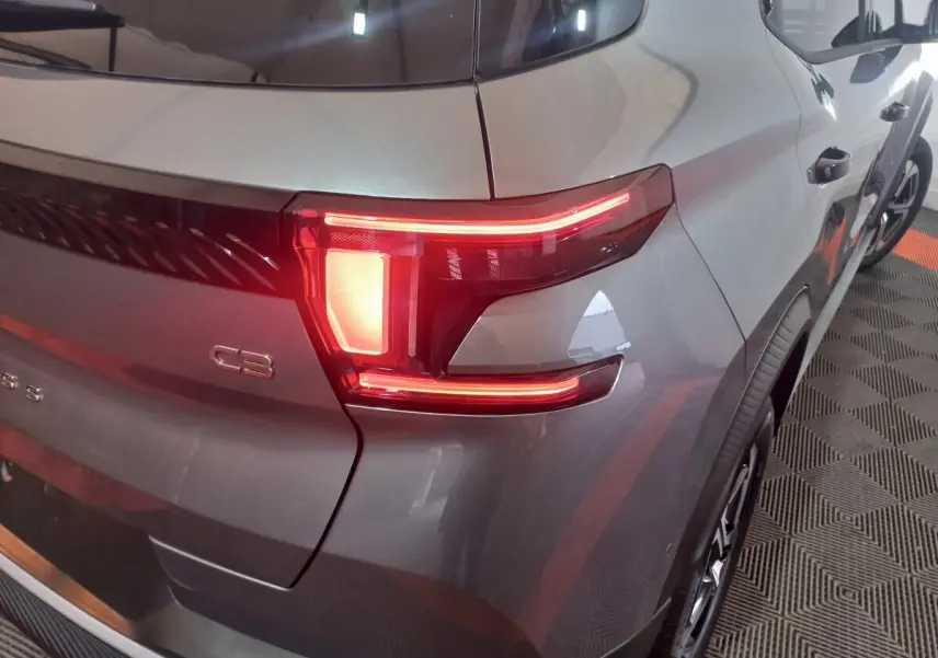 Vue 3/4 arrière droit d'une Citroën C3 hybride 2025 gris foncé, mettant en valeur le feu arrière LED distinctif.