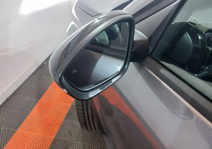 Rétroviseur côté conducteur d'une Citroën C3 hybride gris foncé, vue rapprochée en angle avant gauche.