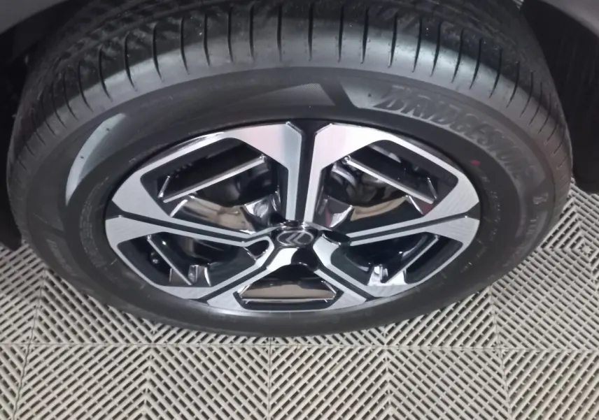 Gros plan sur la jante alliage noire et argentée d'une Citroën C3 hybride gris foncé, avec pneu Bridgestone visible.