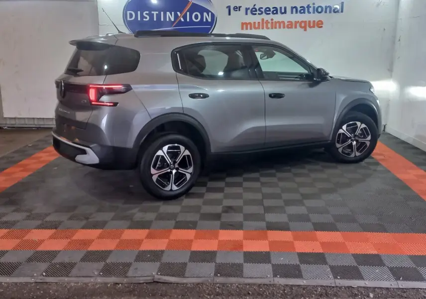 Vue de profil droit d'un Citroën C3 gris foncé hybride 2025, avec jantes modernes et feux arrière allumés.