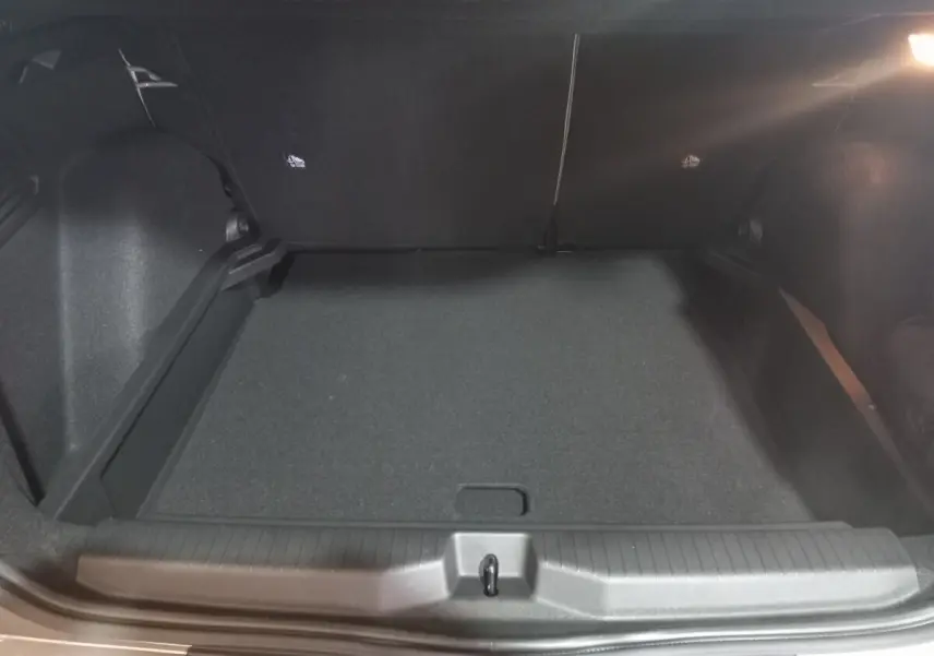 Coffre spacieux de Citroën C3 Hybride gris foncé vu de l'arrière, avec banquette arrière rabattue et éclairage intérieur.