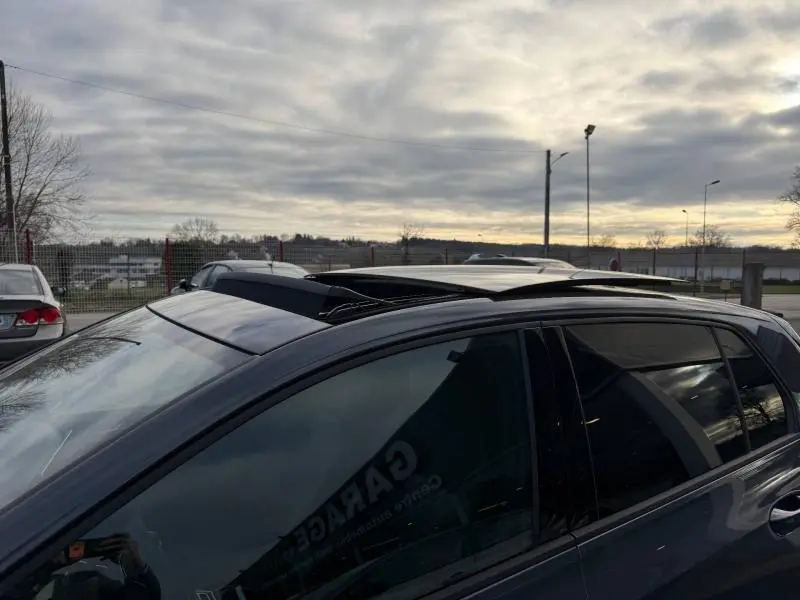 Vue latérale côté gauche d'une Volkswagen Golf gris métallisé 2025 avec toit ouvrant panoramique ouvert.