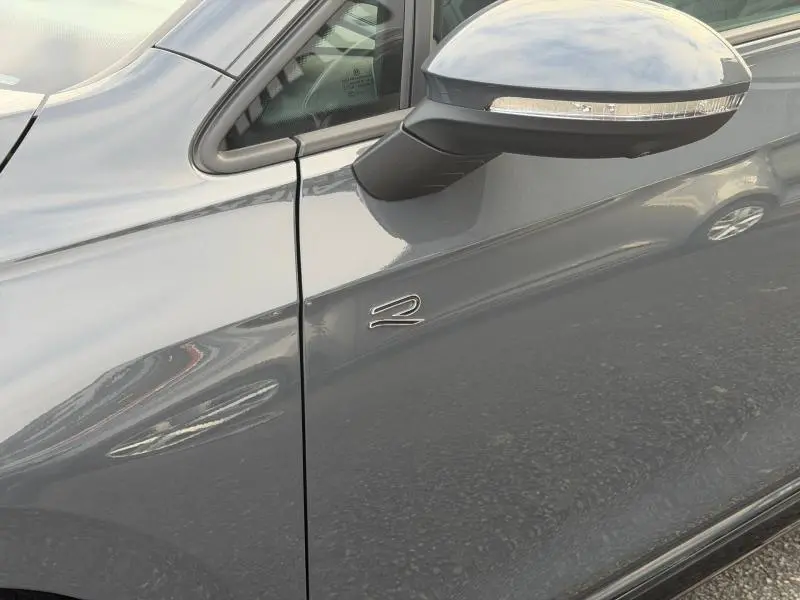 Détail du côté gauche gris d'une Volkswagen Golf 1.5 eTSI R-Line 2025 avec logo R près du rétroviseur.