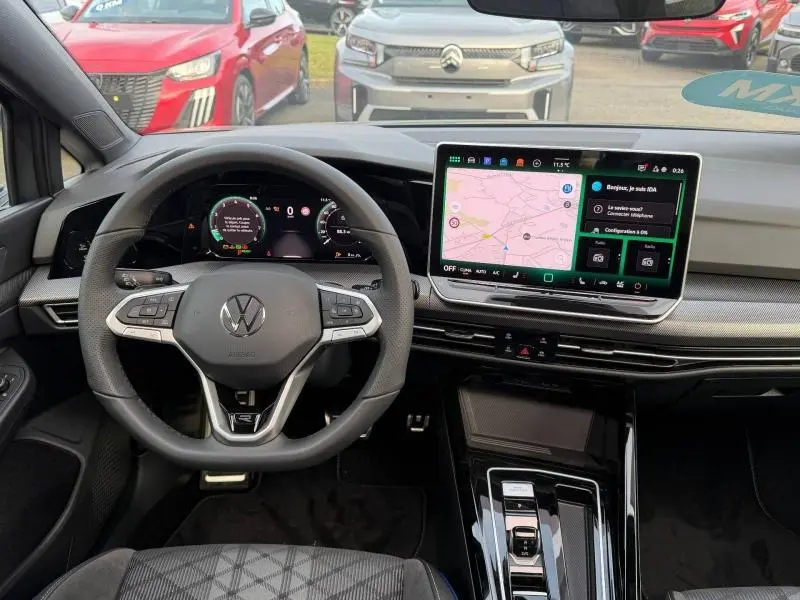 Vue intérieure du tableau de bord de la Volkswagen Golf 1.5 eTSI R-Line 2025 avec écran tactile et volant multifonction noir.