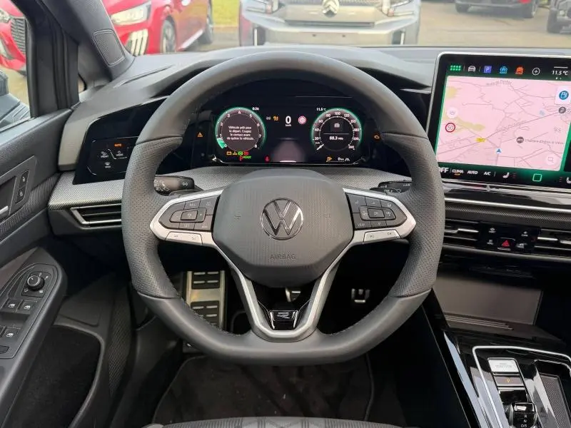 Vue centrée sur le volant de la Volkswagen Golf 1.5 eTSI R-Line 2025, avec tableau de bord numérique et écran tactile de navigation.