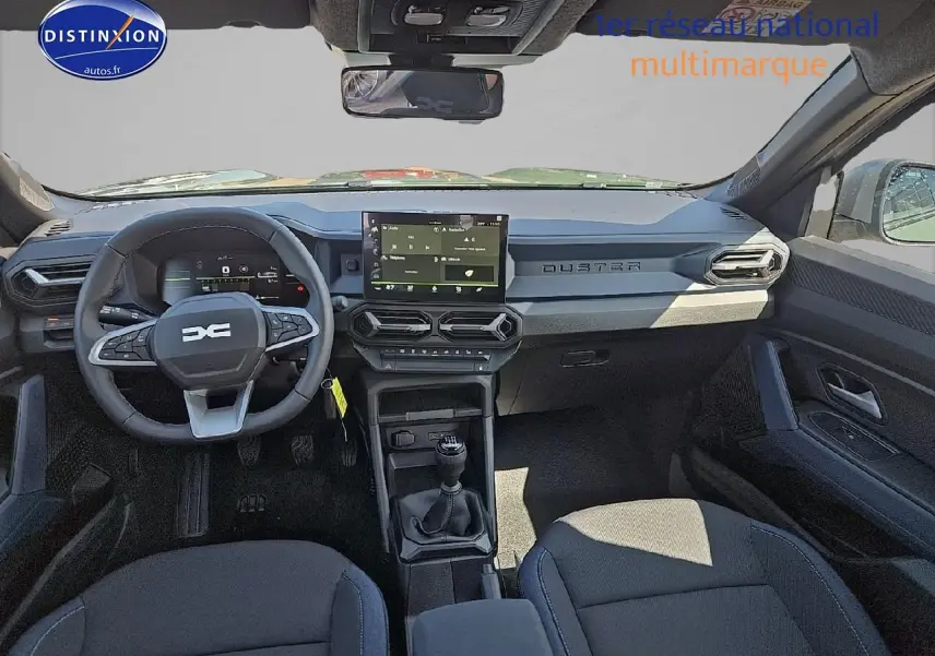 Vue intérieure avant du Dacia Duster 2025 avec tableau de bord moderne, écran tactile et volant multifonction noir.