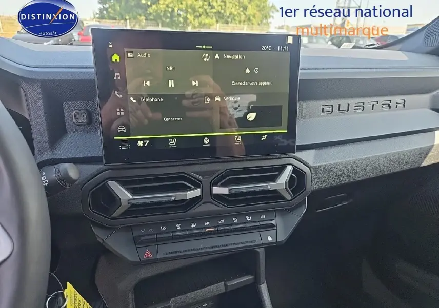 Vue intérieure du tableau de bord du Dacia Duster 2025 avec écran tactile et inscription DUSTER sur la planche de bord.