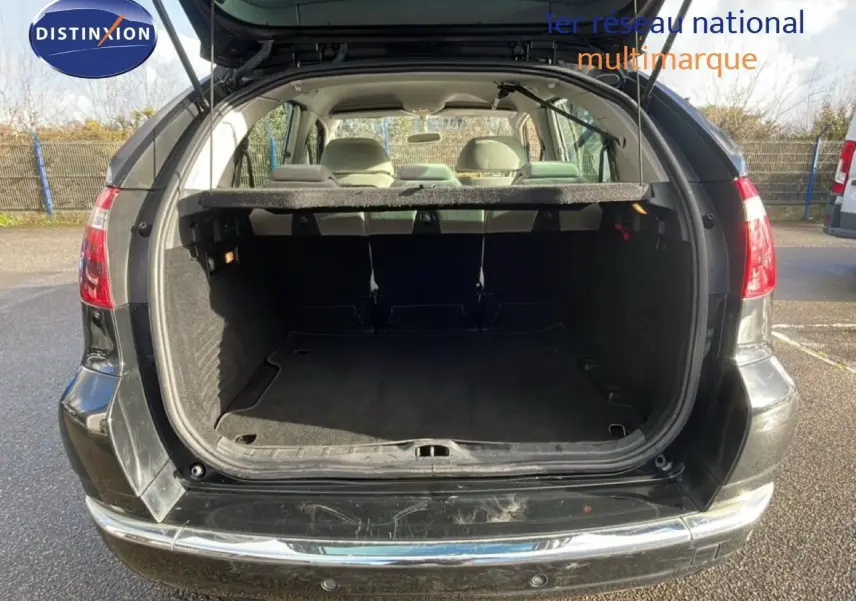 Coffre ouvert vu de l'arrière d'une Citroën C4 Picasso noire métal de 2008, montrant l'espace de chargement vide.