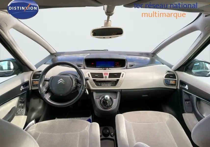 Vue intérieure avant de la Citroën C4 Picasso 2008, tableau de bord beige et noir avec volant cuir et levier de vitesse manuel.