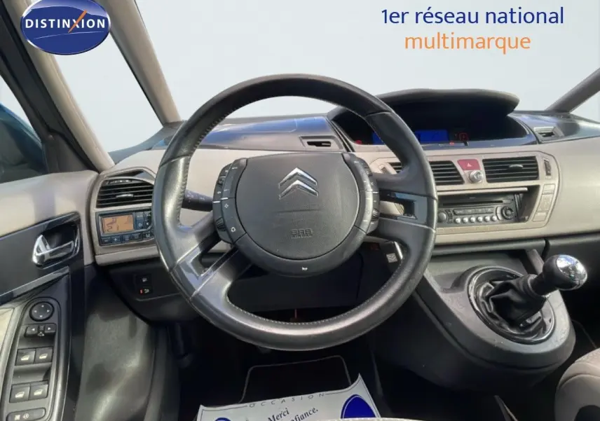 Vue intérieure du poste de conduite de la Citroën C4 Picasso 2008, volant cuir noir et levier de vitesse manuel visible.
