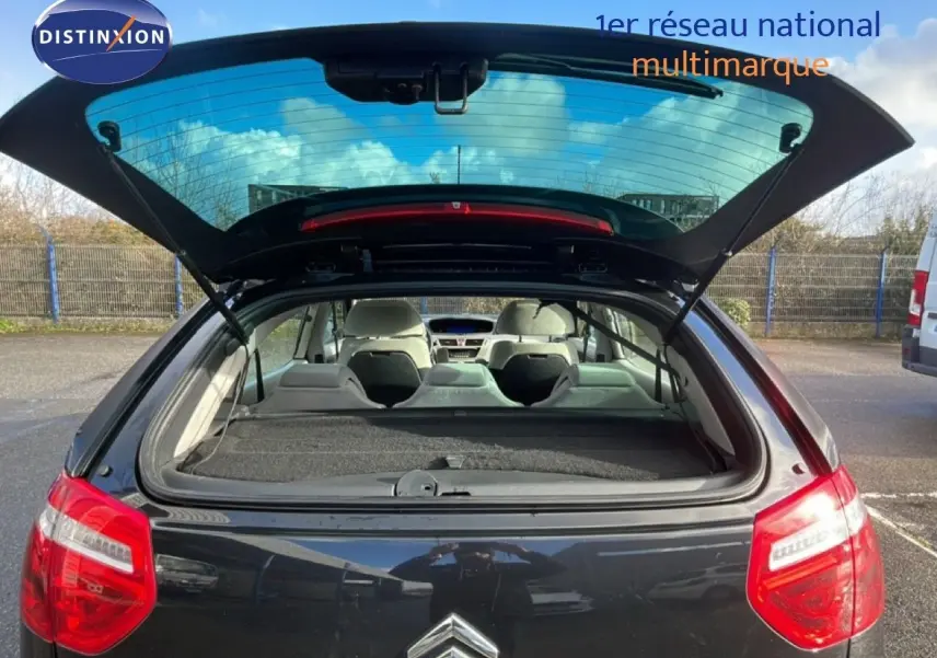 Vue arrière ouverte d'une Citroën C4 Picasso noire métal, montrant l'intérieur et le hayon relevé en extérieur.