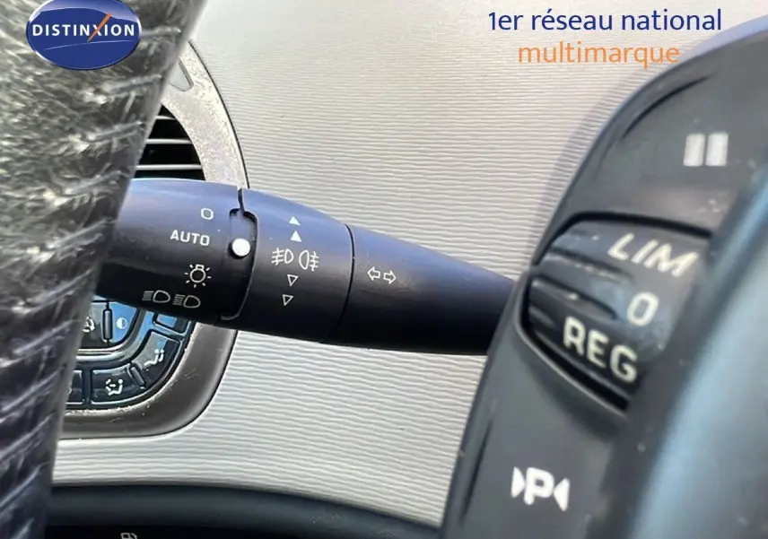 Gros plan sur la manette de clignotant et commandes au volant d'une Citroën C4 Picasso noire, intérieur beige.