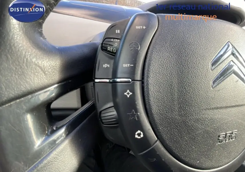 Gros plan sur le volant en cuir noir du Citroën C4 Picasso 2008, montrant les commandes intégrées côté gauche.