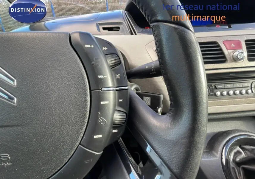 Gros plan sur le volant cuir noir et la console centrale beige du Citroën C4 Picasso 2008, version Exclusive.