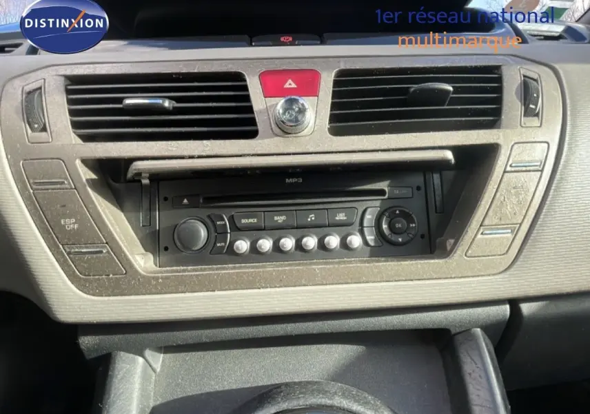 Vue rapprochée du tableau de bord beige et noir du Citroën C4 Picasso 2008 avec autoradio MP3 et commandes centrales.